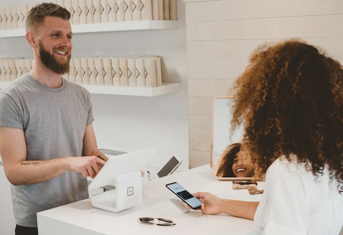Customer paying by phone at a shop counter